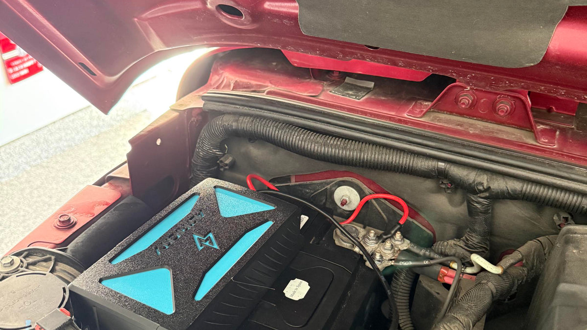 Altricity remote jump starter permanently installed beside the battery under the hood of a red Jeep